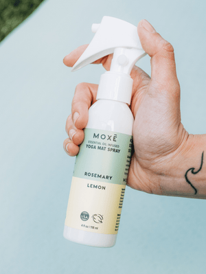 Hand holding the MOXĒ Rosemary Lemon Yoga Mat Spray 